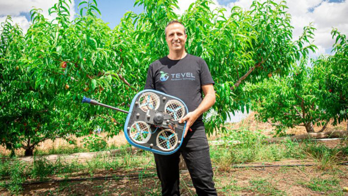 Генеральный директор Tevel Янив Маор с летающим дроном для сбора фруктов в саду.