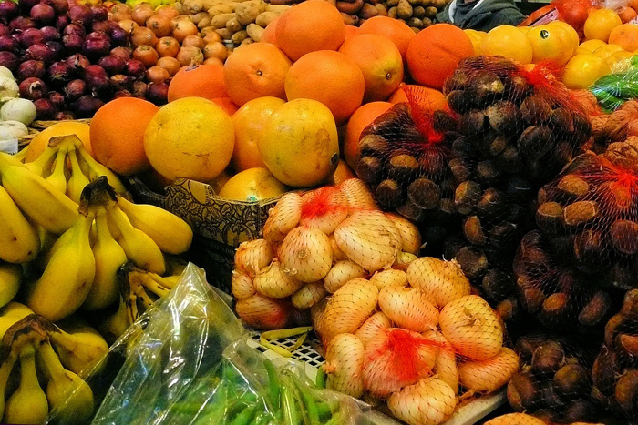 Фрукты, овощи и орехи разных видов лежат на прилавке в магазине.