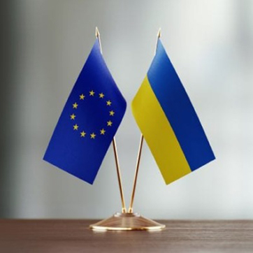 Флажки ЕС и Украины стоят на подставке на столе.