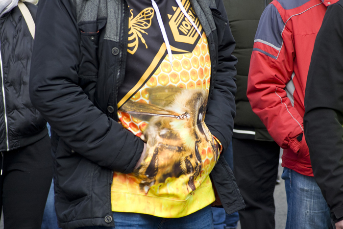 Чоловік у чорній куртці й футболці із зображенням бджоли.