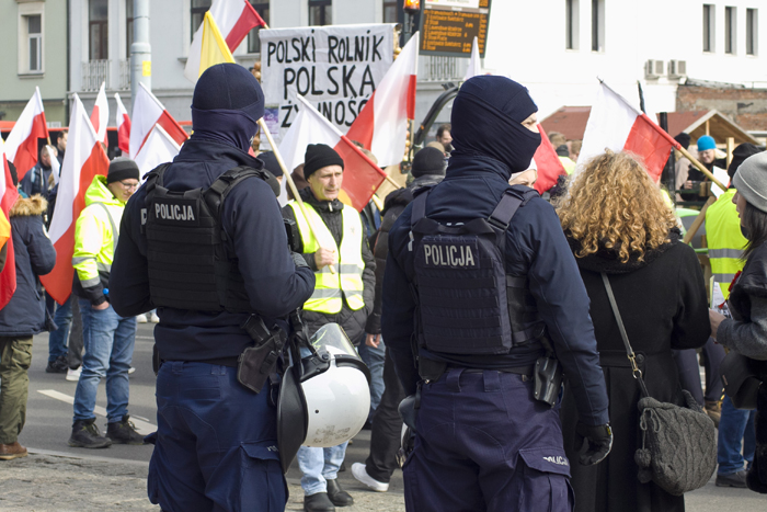 Два полицейских на фоне колонны участников протеста фермеров в Гданьске.