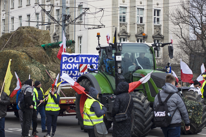 Протестующие фермеры на фоне трактора с инсталляцией в виде танка из соломы.