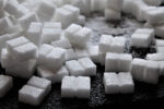 Кусочки белого сахара-рафинада лежат на черном столе.