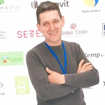 Підприємець Іван Дегтяр на фоні виставочного банеру з різними логотипами.