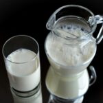 Скляний глечик і склянка з молоком стоять на чорному фоні.