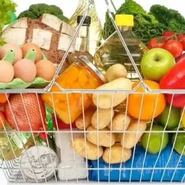 Разные продукты лежат в корзинке супермаркета.